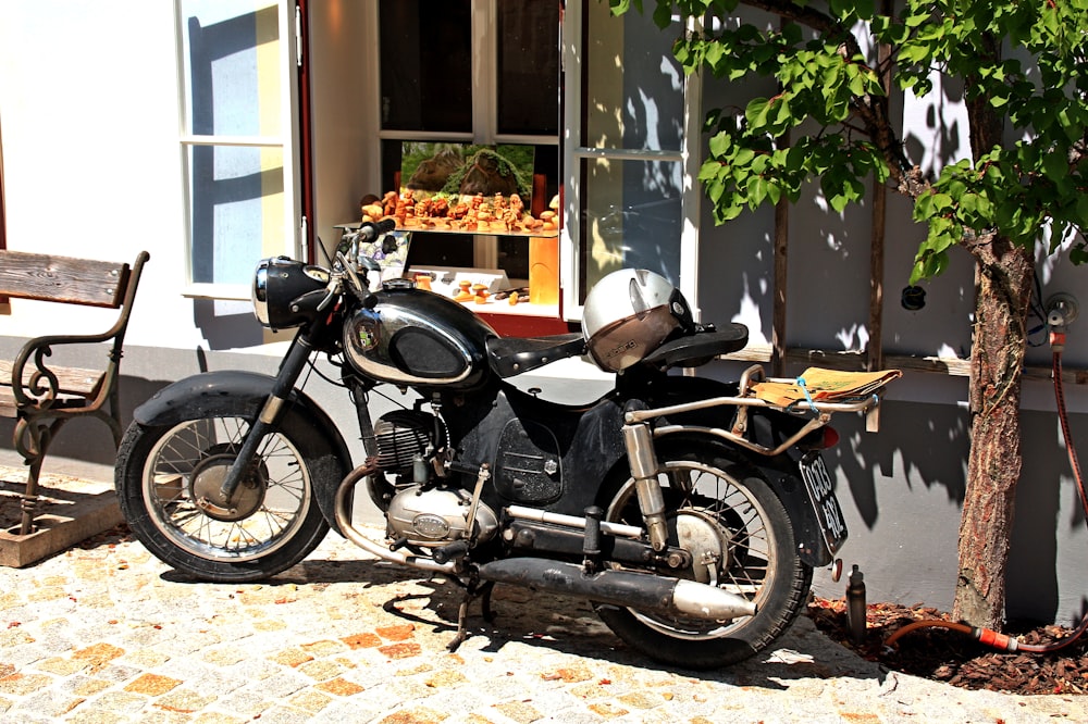 black and gray motorcycle parked beside green plants during daytime