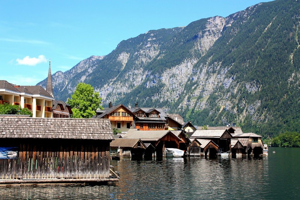 brown wooden houses on lake near green mountains during daytime