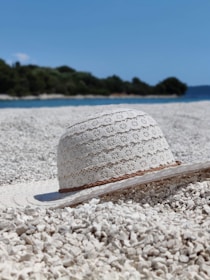 A collection of beachhead summer hats displayed on a sandy shore with the soft glow of sunset in the background.