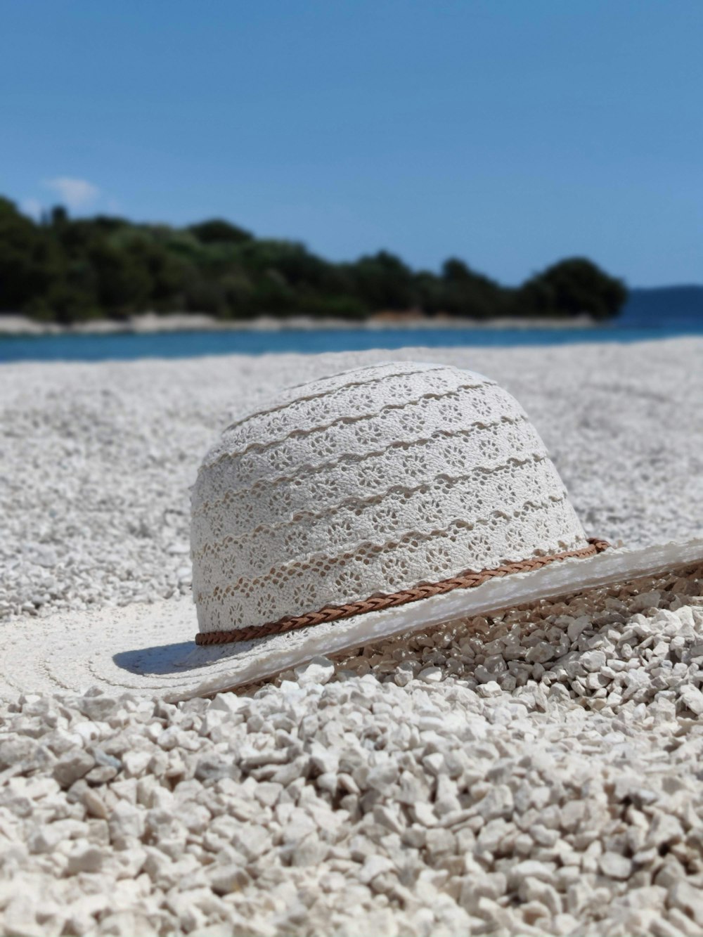 white and blue sun hat on white sand beach during daytime