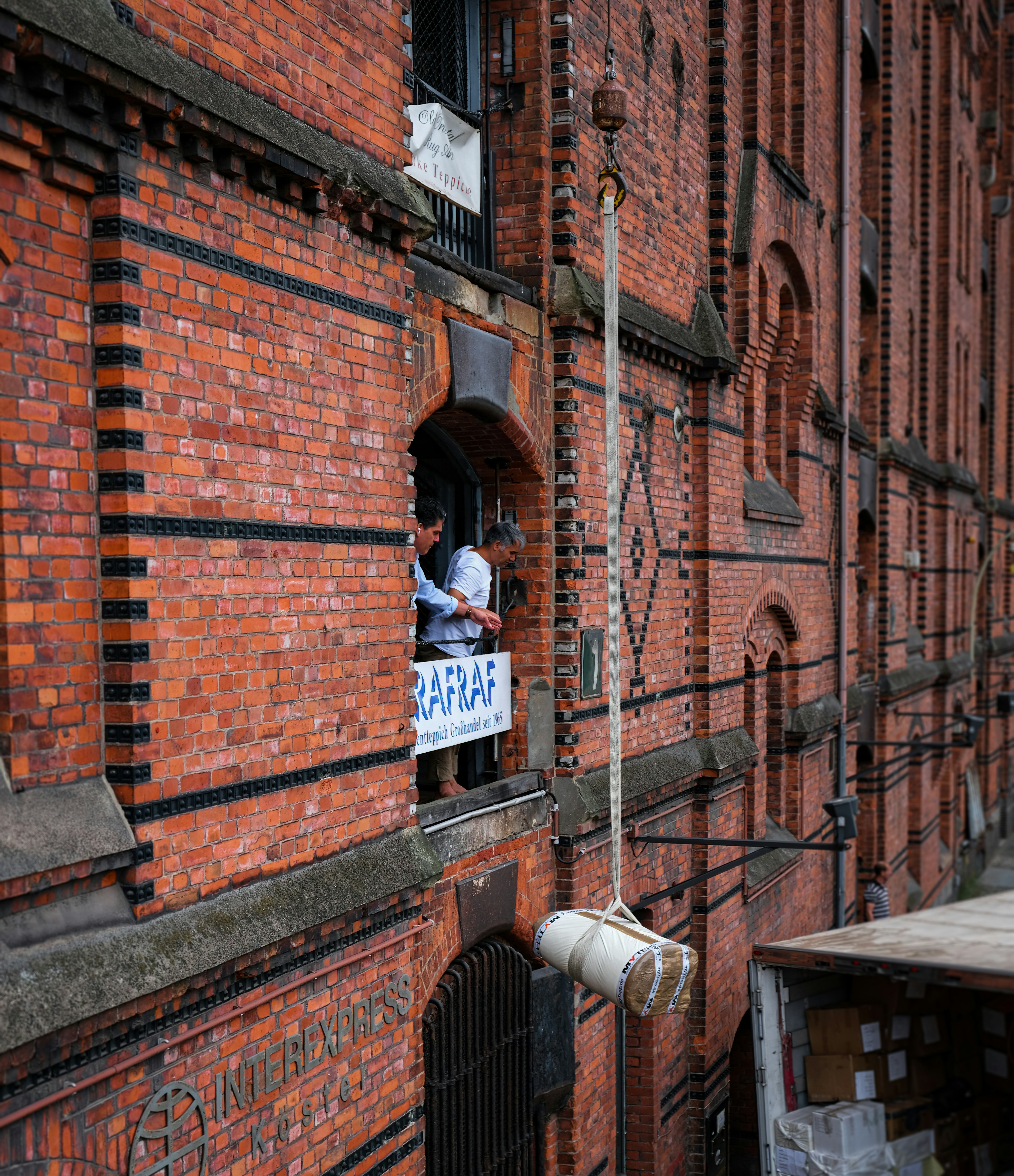 man in black jacket standing on brown brick building during daytime