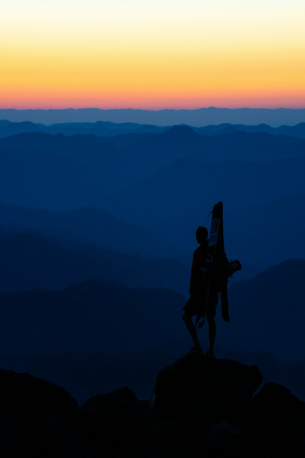 silhouette of 2 person standing on top of mountain during sunset