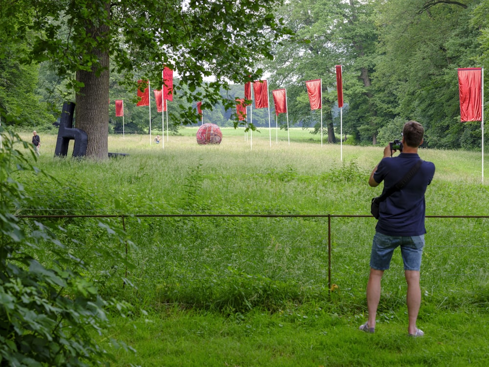 man in black shirt and blue denim shorts standing on green grass field