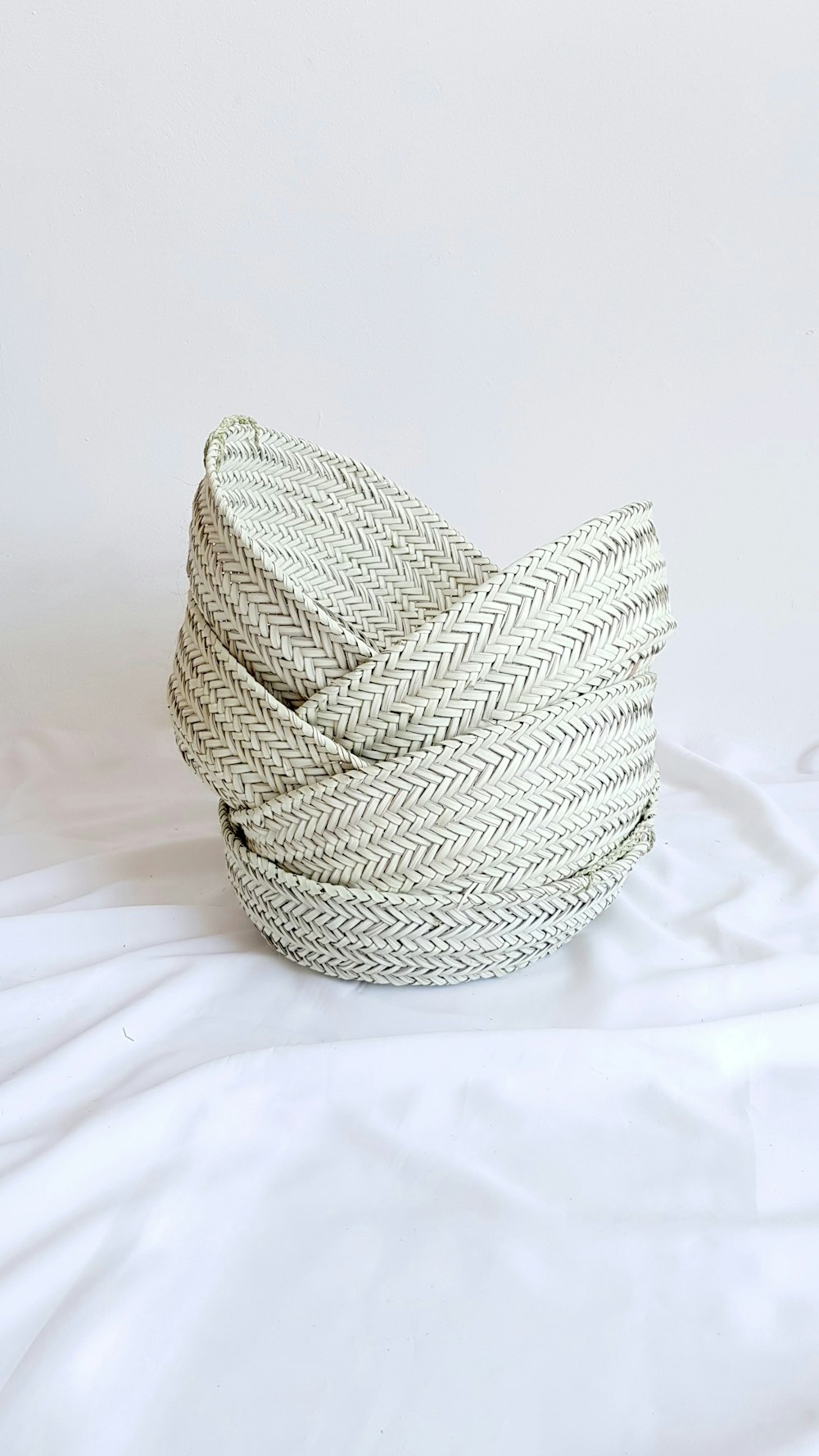 gray woven round basket on white textile