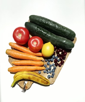 red tomato beside green cucumber and red tomato on brown wooden chopping board