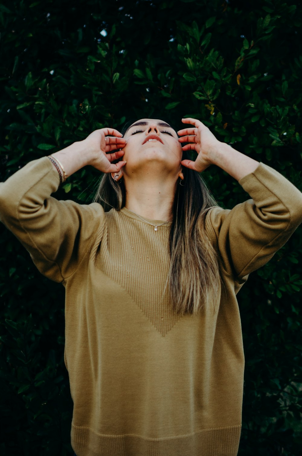 woman in brown long sleeve shirt standing near green plant