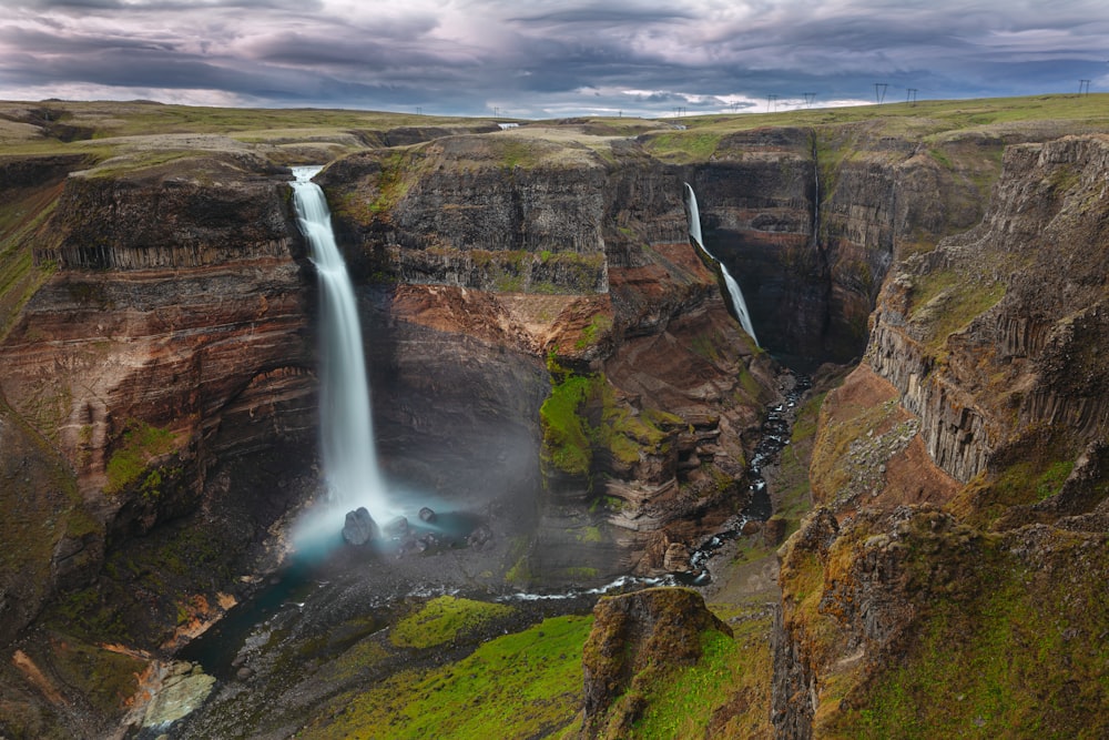 waterfalls on brown rocky mountain under gray cloudy sky during daytime