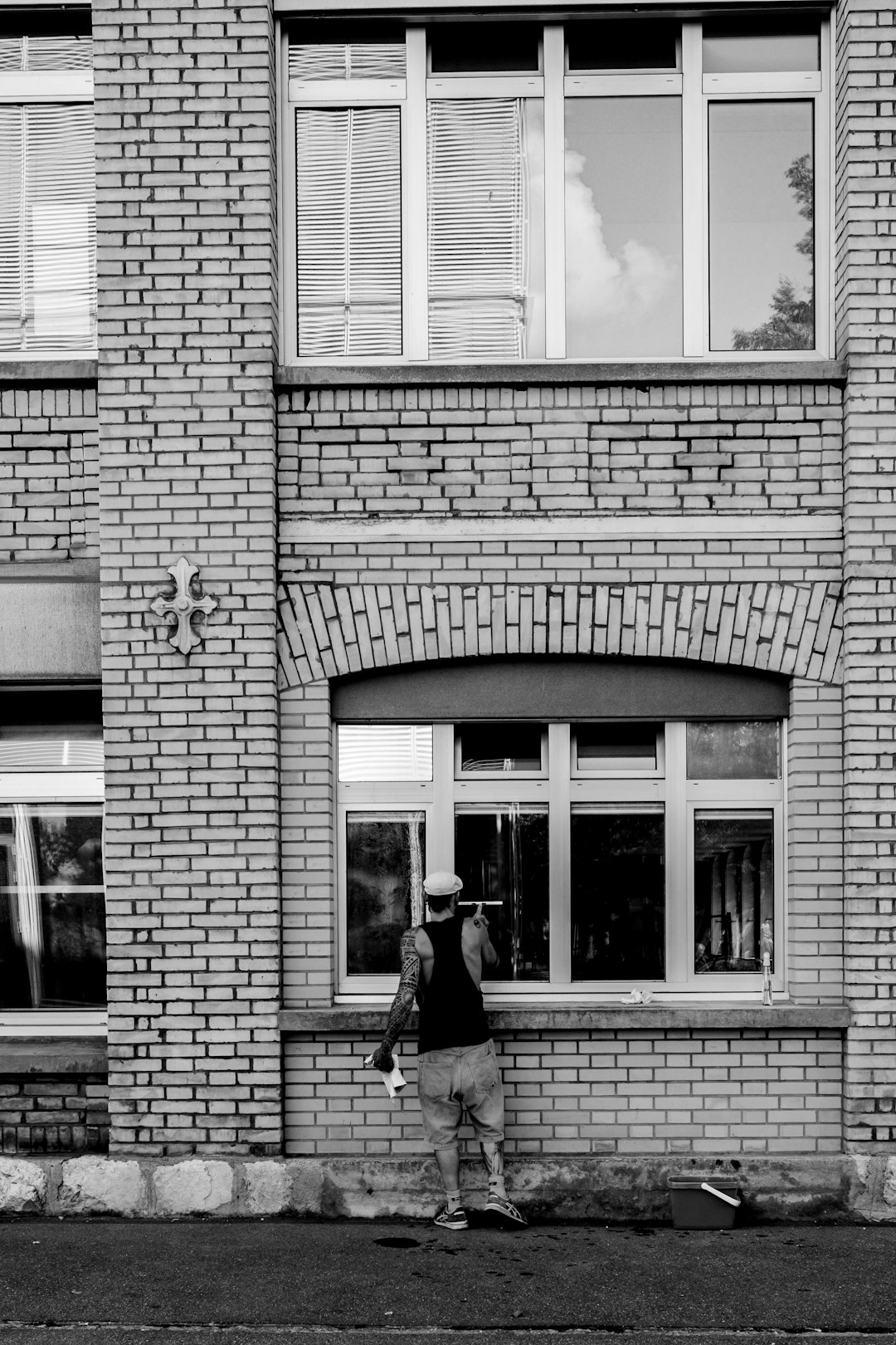 grayscale photo of woman walking in front of building