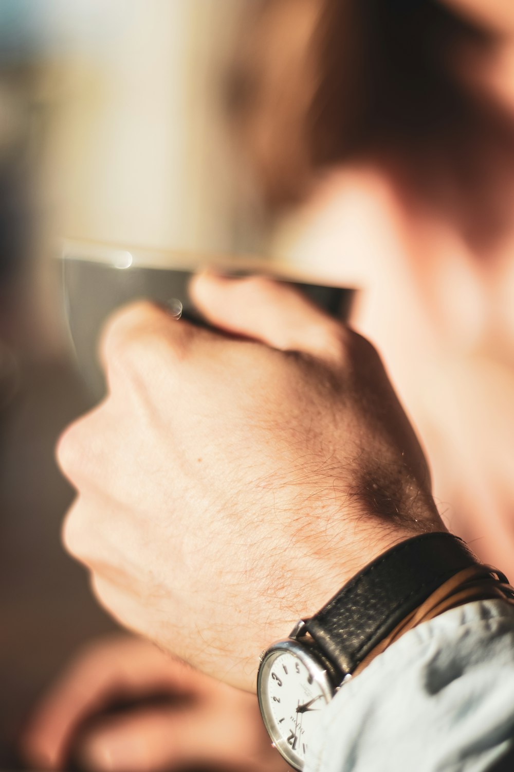 person wearing black watch holding clear drinking glass