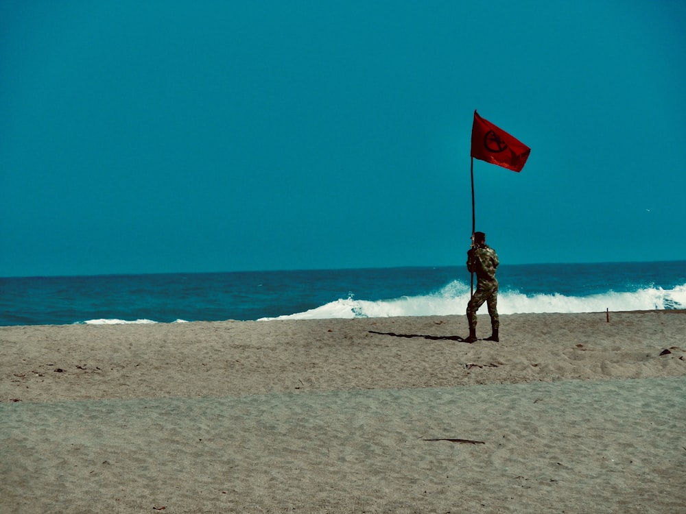 낮 동안 해변에 서 있는 붉은 깃발을 들고 있는 흑백 드레스를 입은 여자