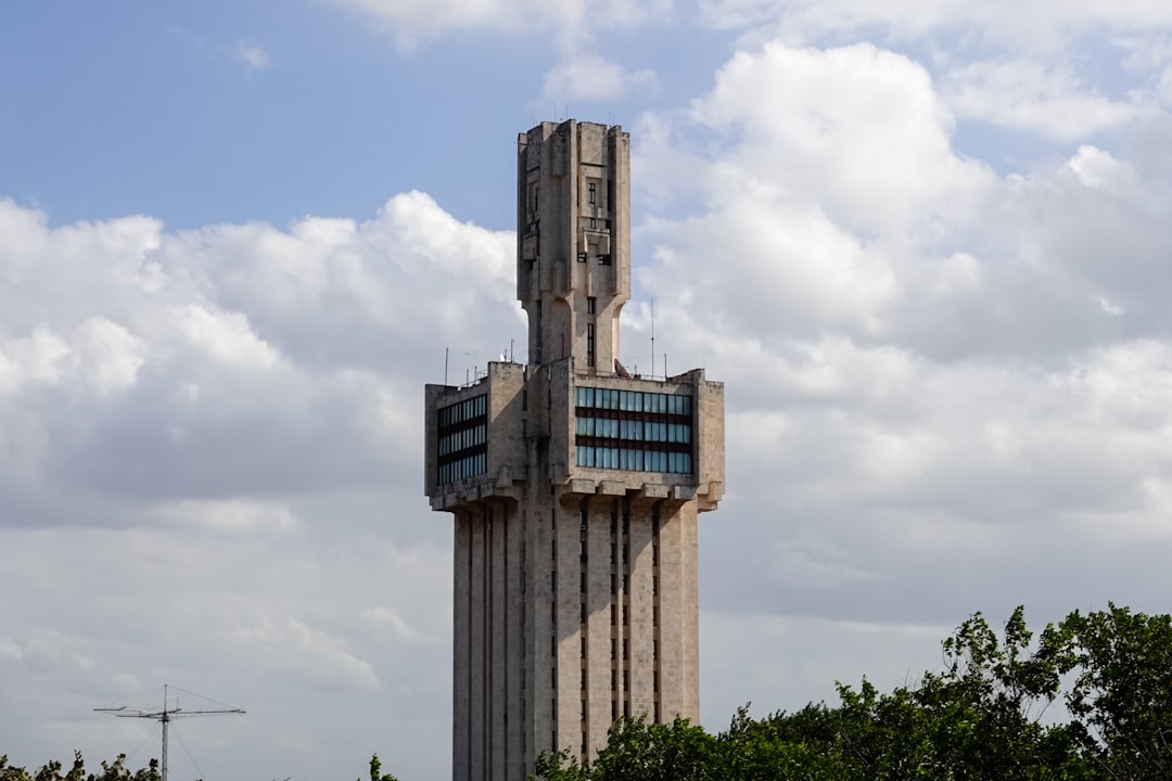 white concrete building under white clouds during daytime