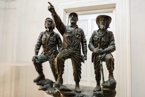 3 men statue standing near white wall