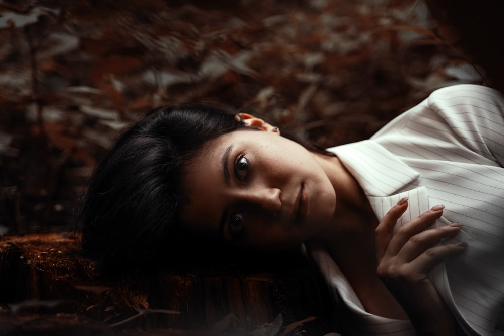 mulher no botão branco para cima camisa deitada em folhas secas