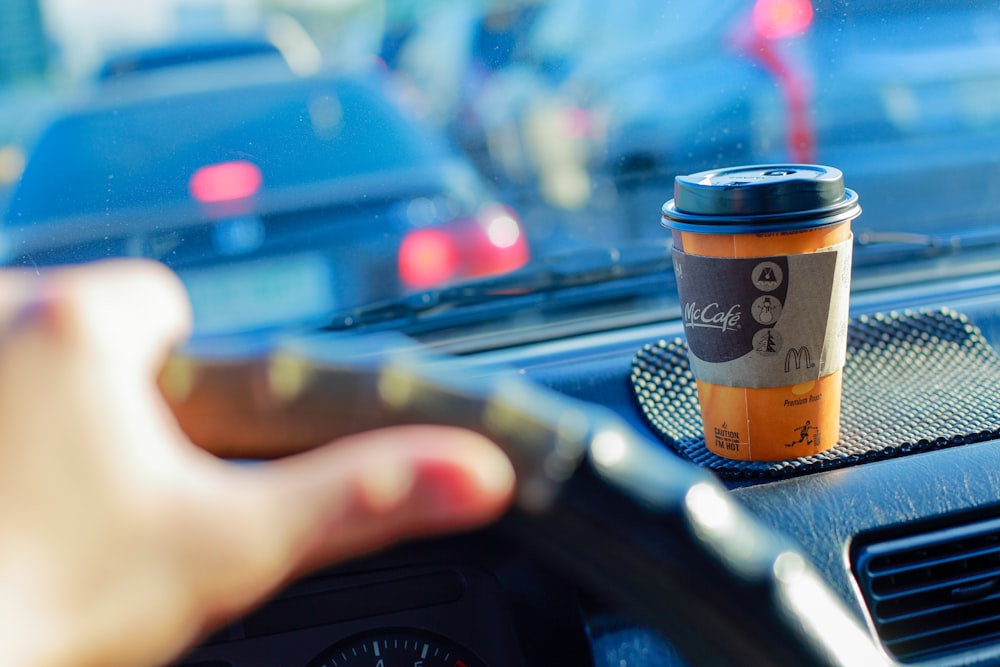 person holding black and brown disposable cup