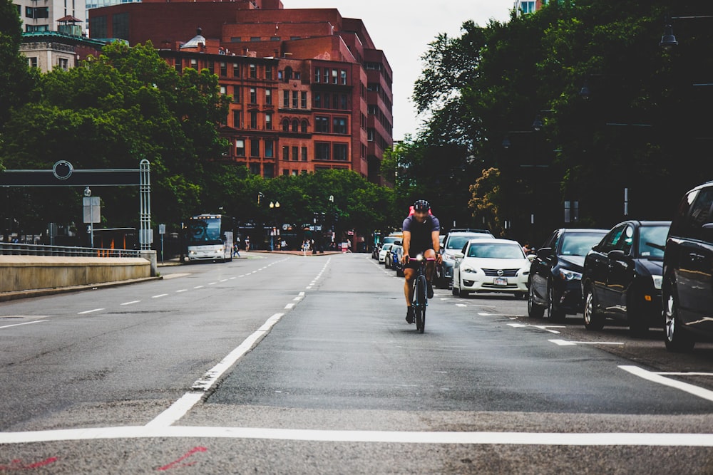 man in black jacket riding bicycle on road during daytime