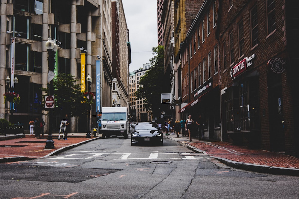 cars parked on side of the road in between buildings during daytime