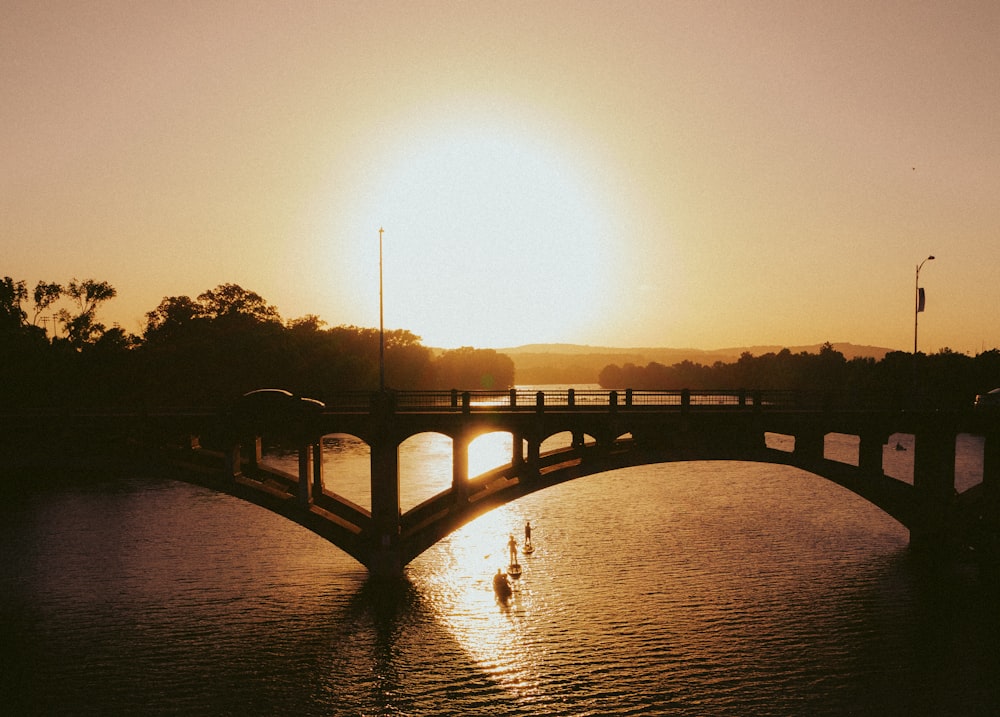 Silueta del puente sobre el agua durante la puesta del sol