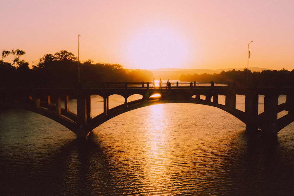 silhouette of bridge over water during sunset