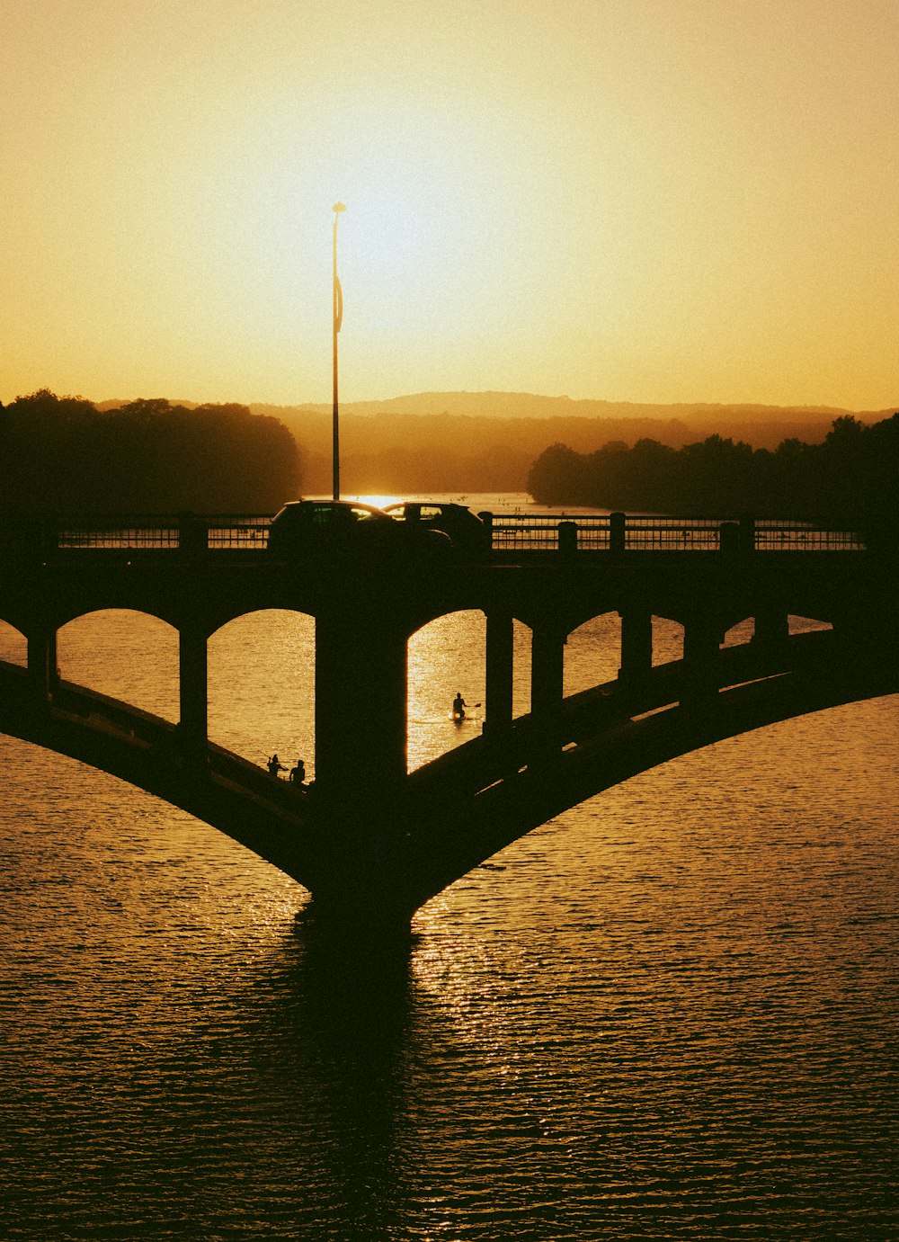 silhouette of bridge over body of water during sunset