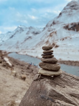 stack of stones on brown sand near snow covered mountain during daytime