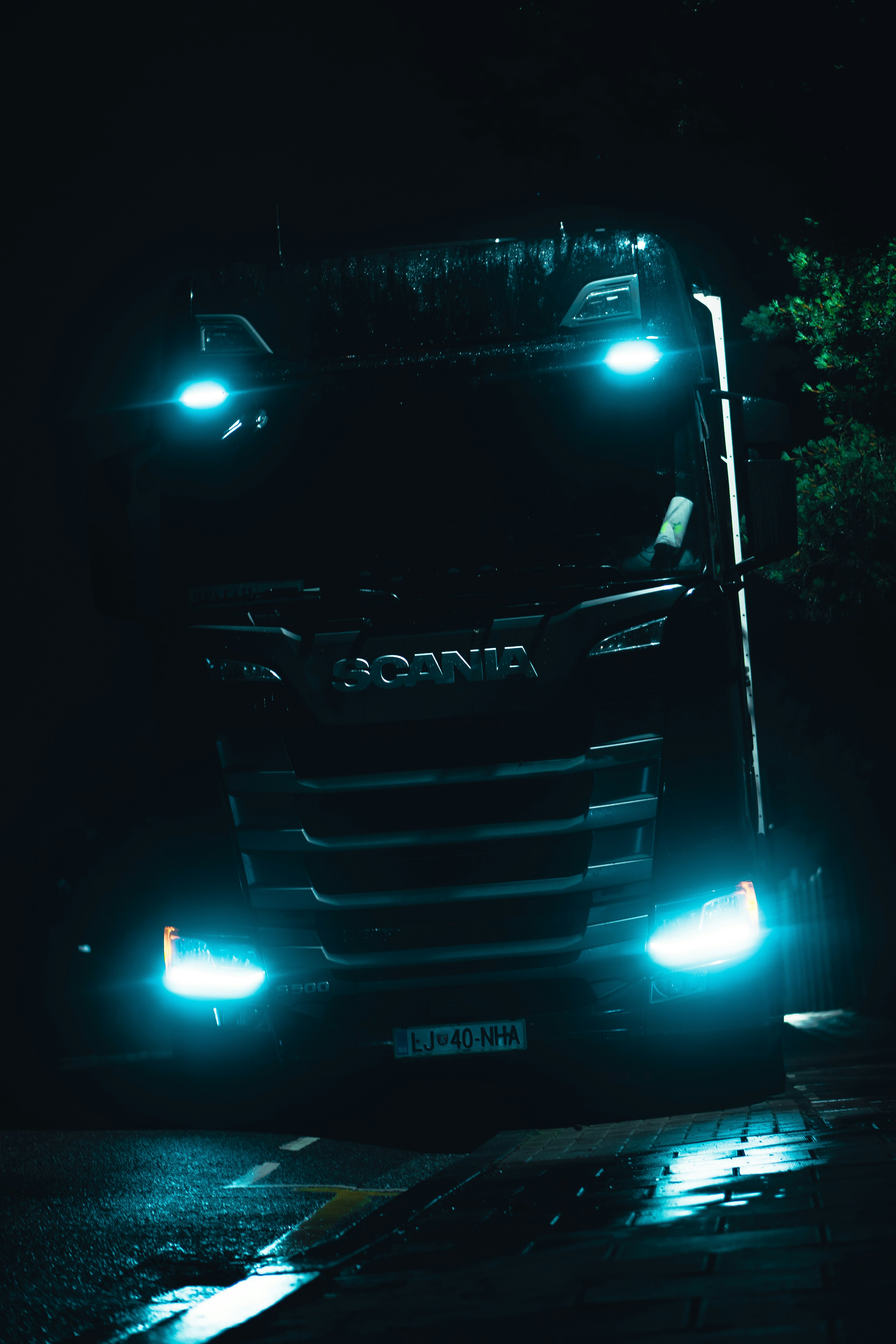 Camión de carga en carretera nocturna, luces de frente, cielo oscuro, cabina iluminada, ambiente profesional de transporte