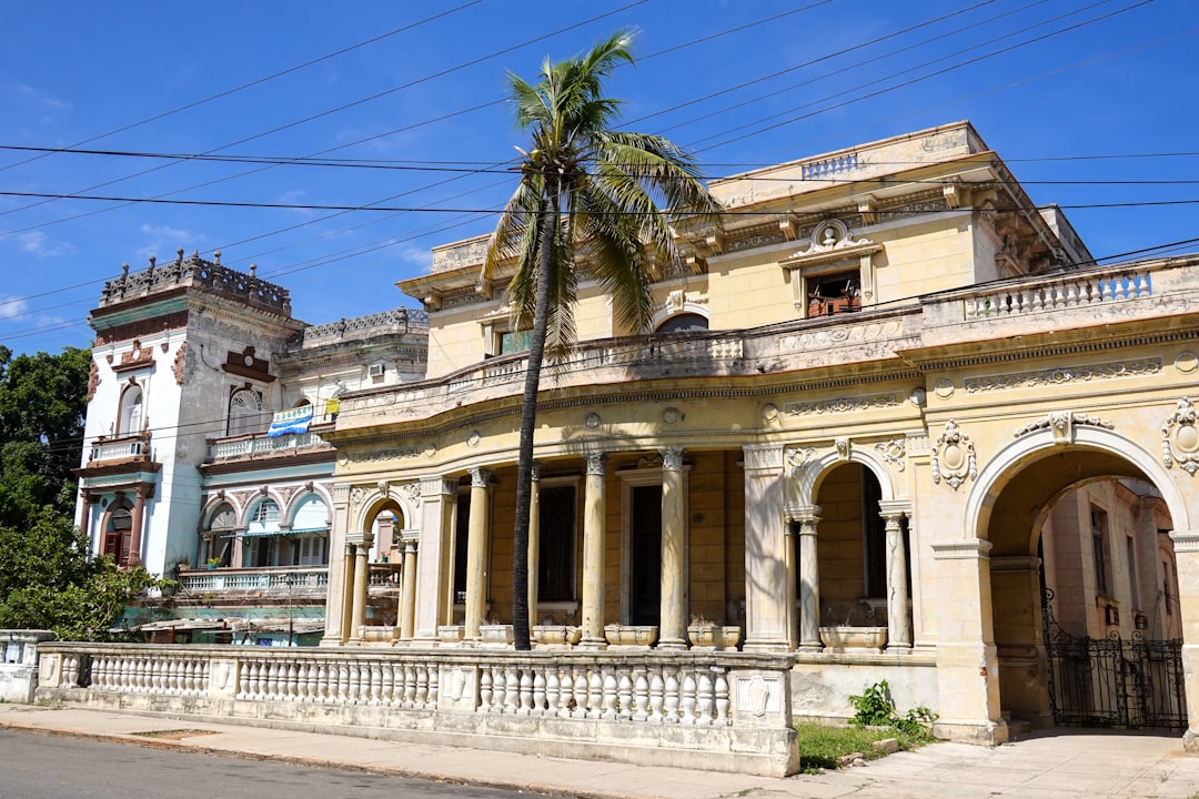 beige concrete building near palm tree under blue sky during daytime