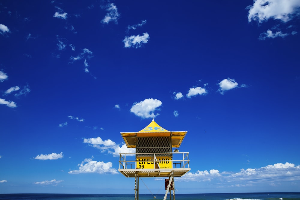 brown wooden lifeguard house on beach under blue sky during daytime