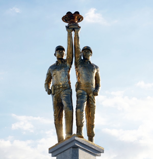 man and woman statue under white clouds during daytime