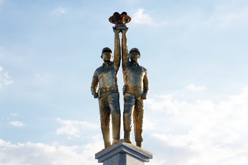 man and woman statue under white clouds during daytime