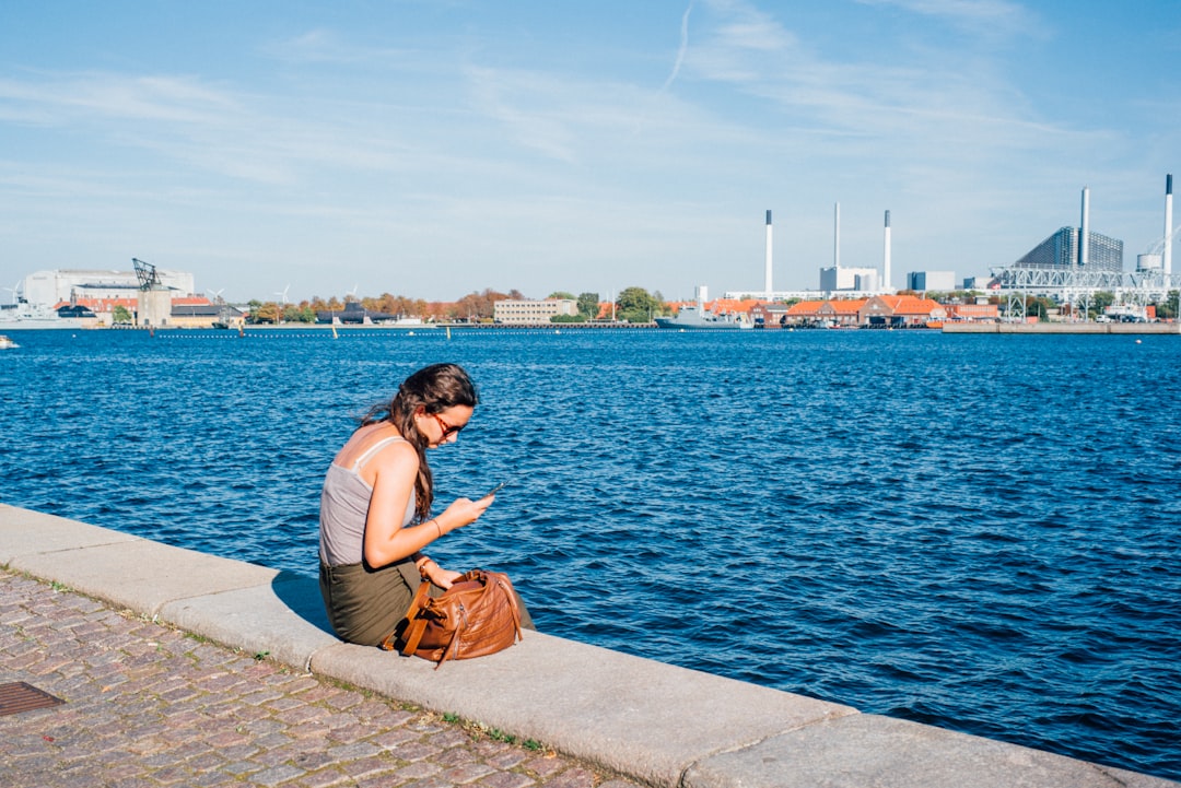 woman in blue tank top sitting on concrete dock during daytime