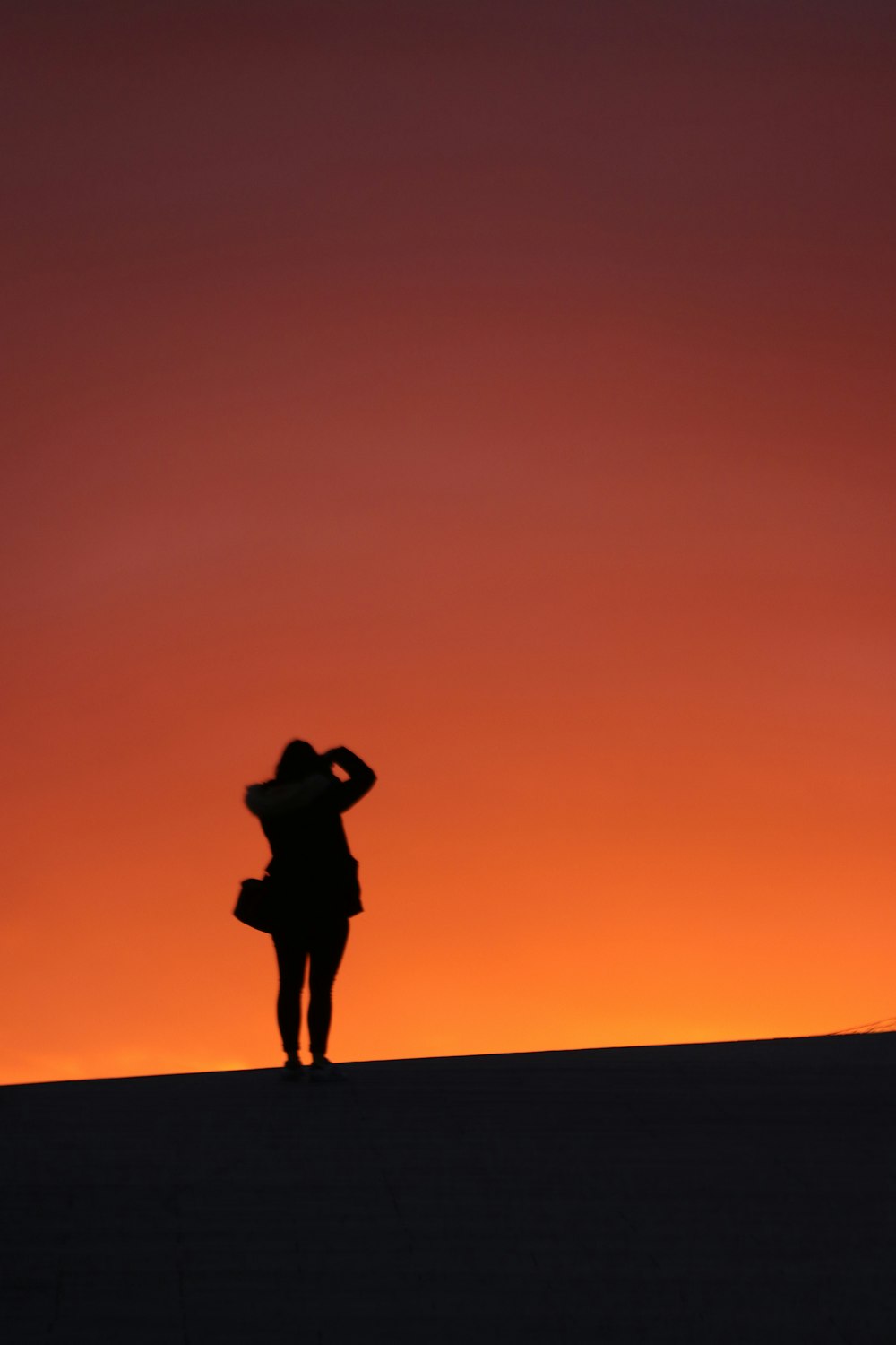 silhouette of man standing on sand during sunset