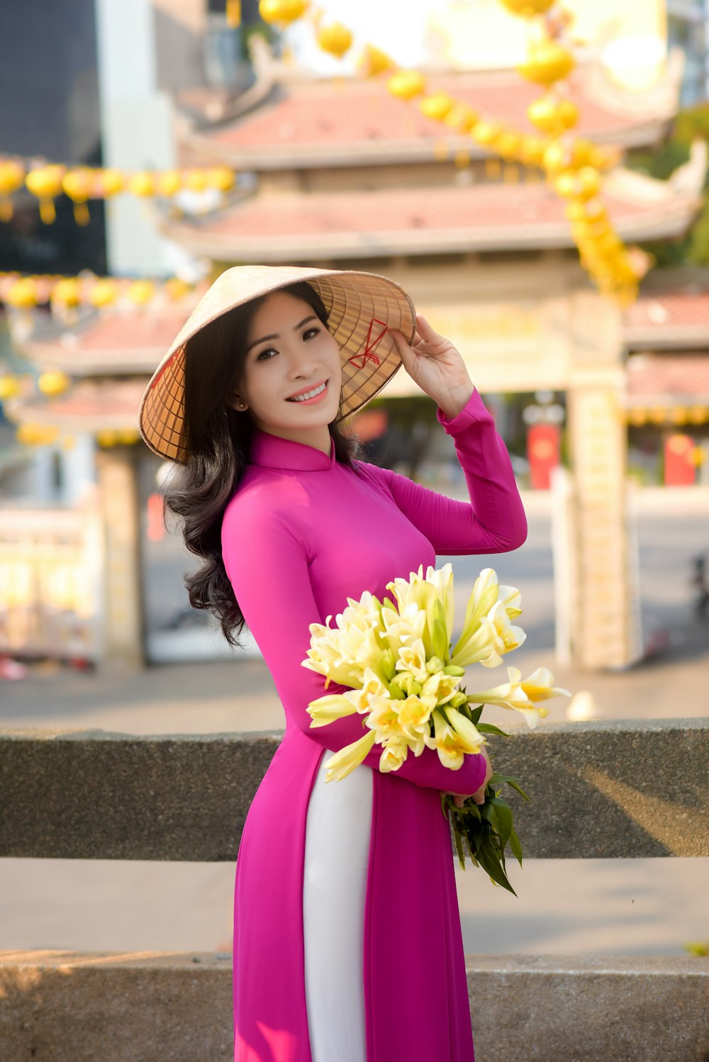 woman in purple long sleeve shirt and brown straw hat holding yellow flower bouquet