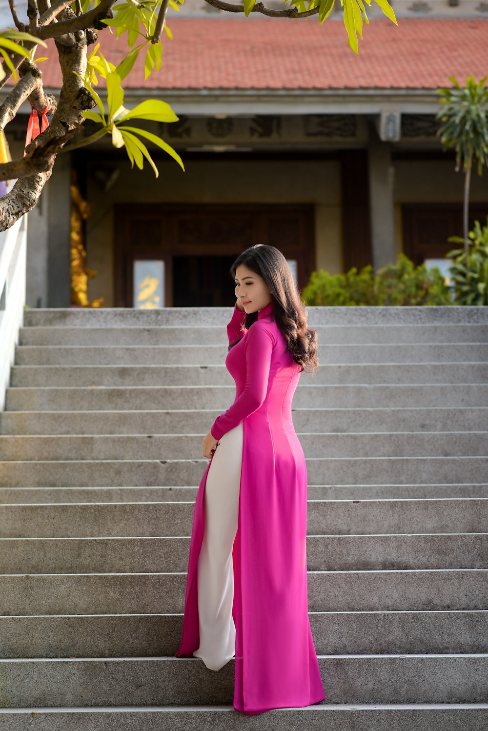Femme en robe rose à manches longues debout sur des escaliers en béton gris