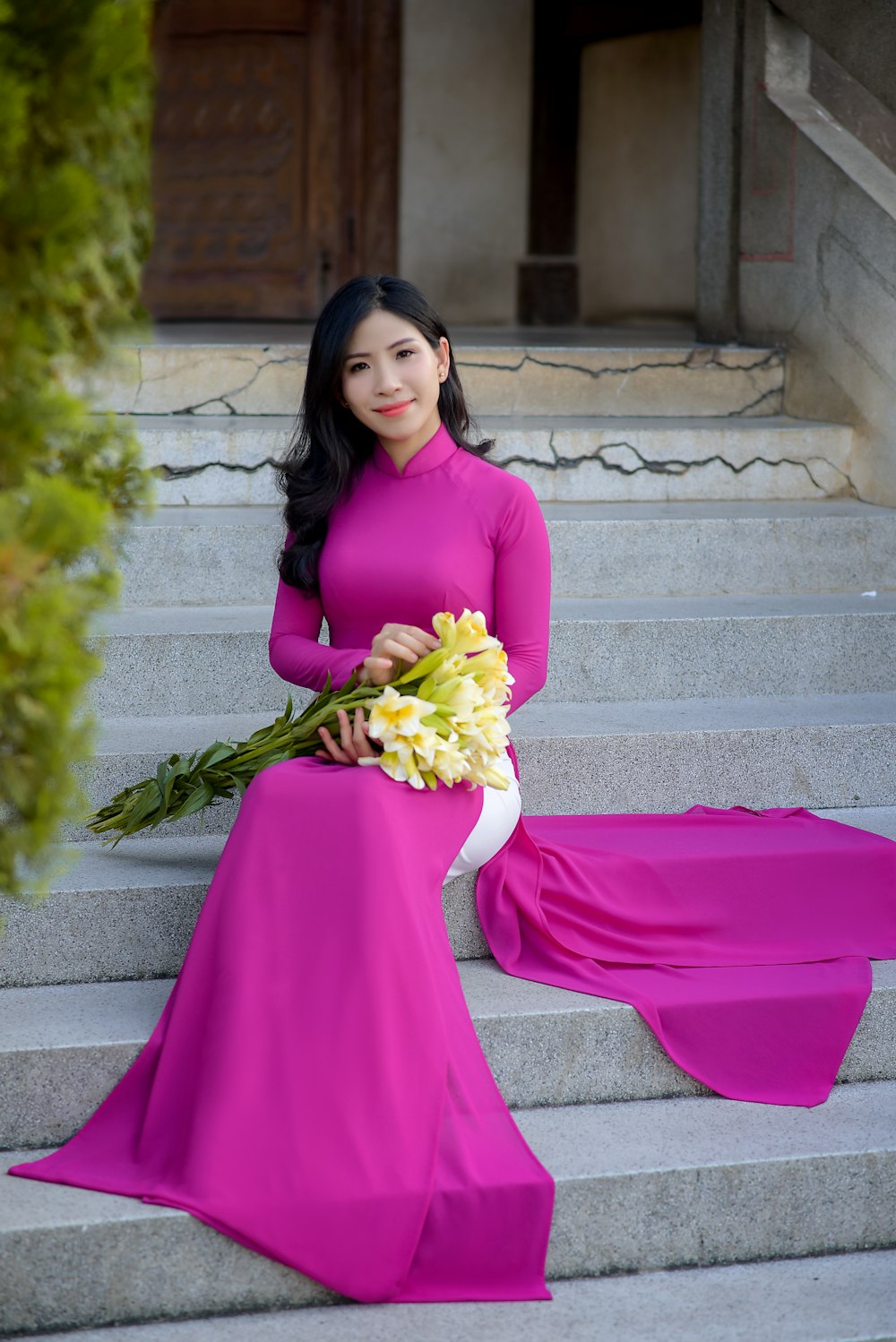 Femme en robe rose à manches longues tenant un bouquet de fleurs