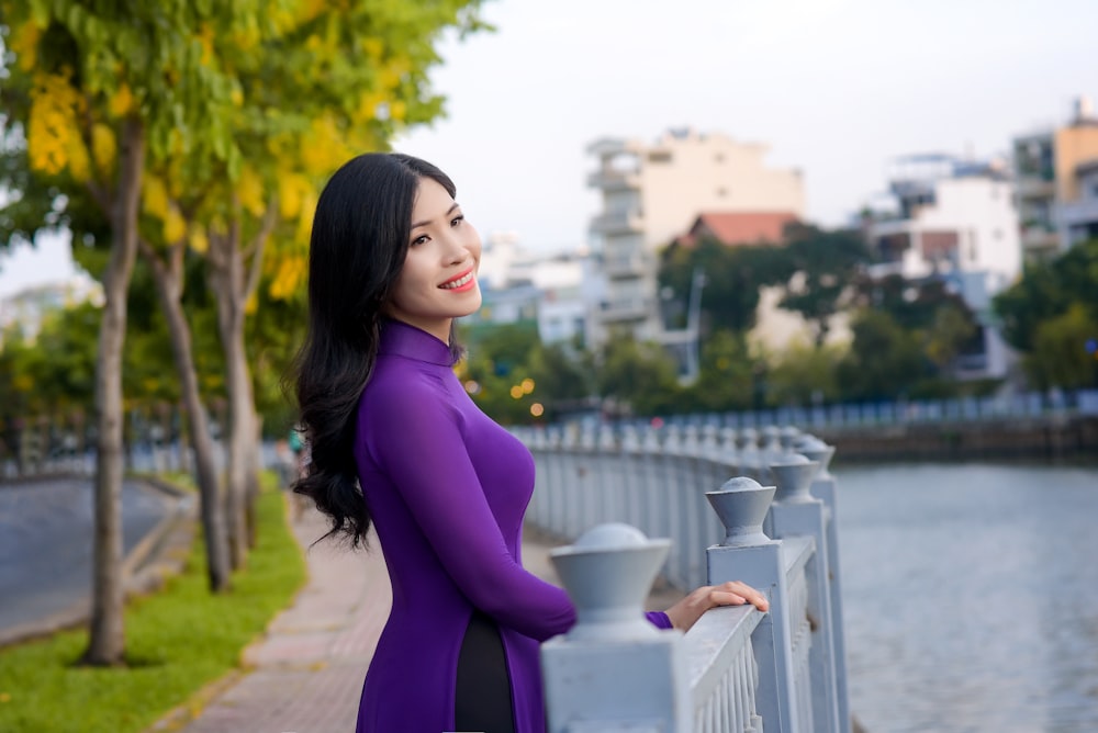 woman in purple long sleeve dress standing near body of water during daytime