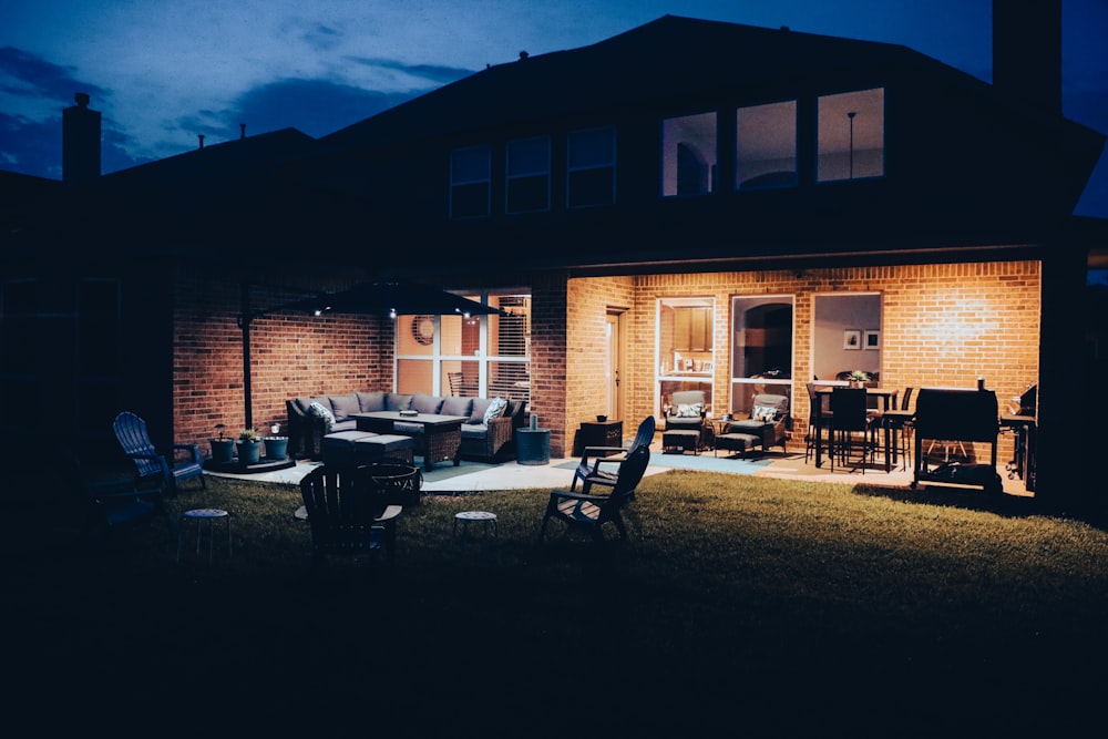 Table et chaises en bois brun près d’un bâtiment en béton brun pendant la nuit