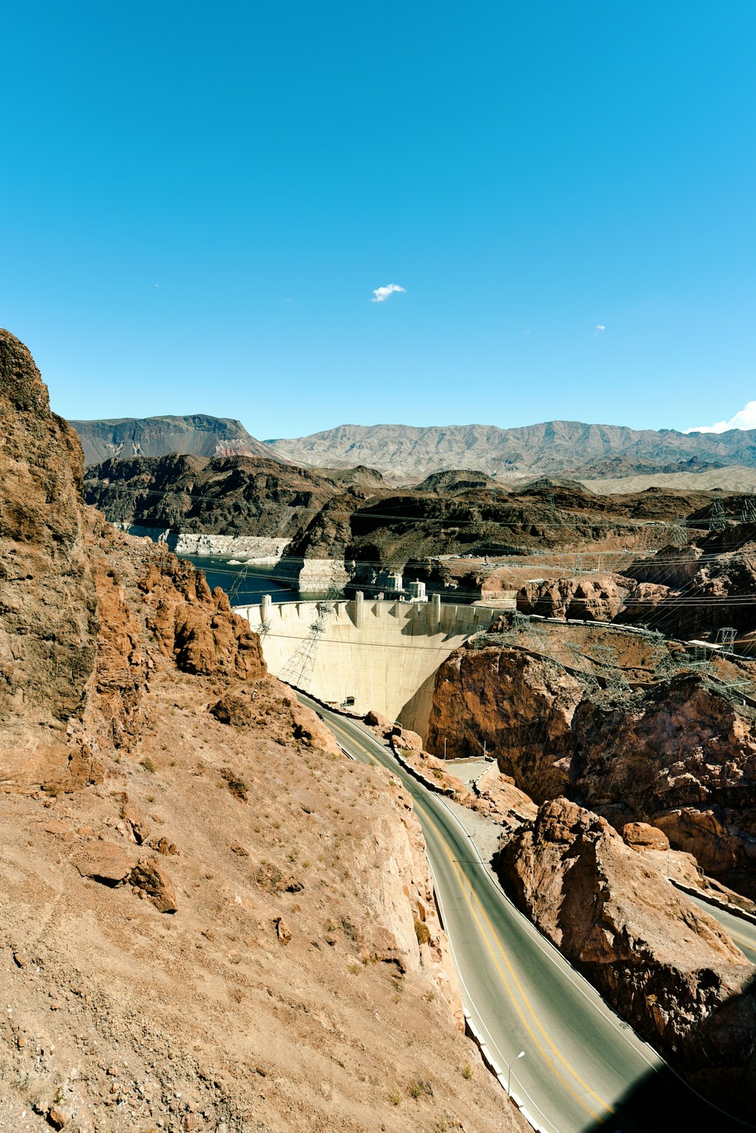 white concrete bridge on brown rocky mountain under blue sky during daytime