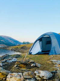 white dome tent on green grass field near body of water during daytime