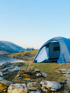 white dome tent on green grass field near body of water during daytime