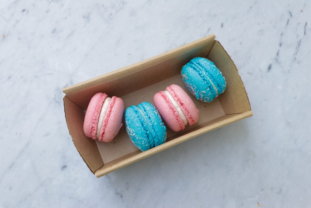 pink and blue round candies in brown box