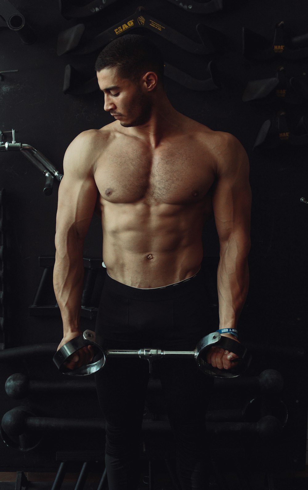 topless man in black shorts holding black and silver dumbbell