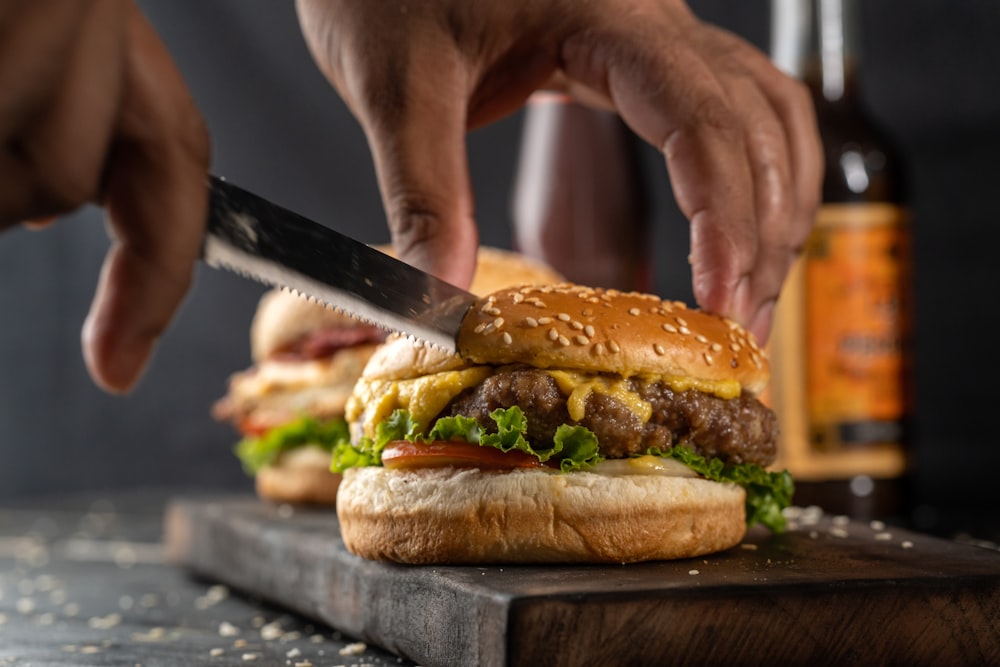 person holding burger with lettuce and tomato