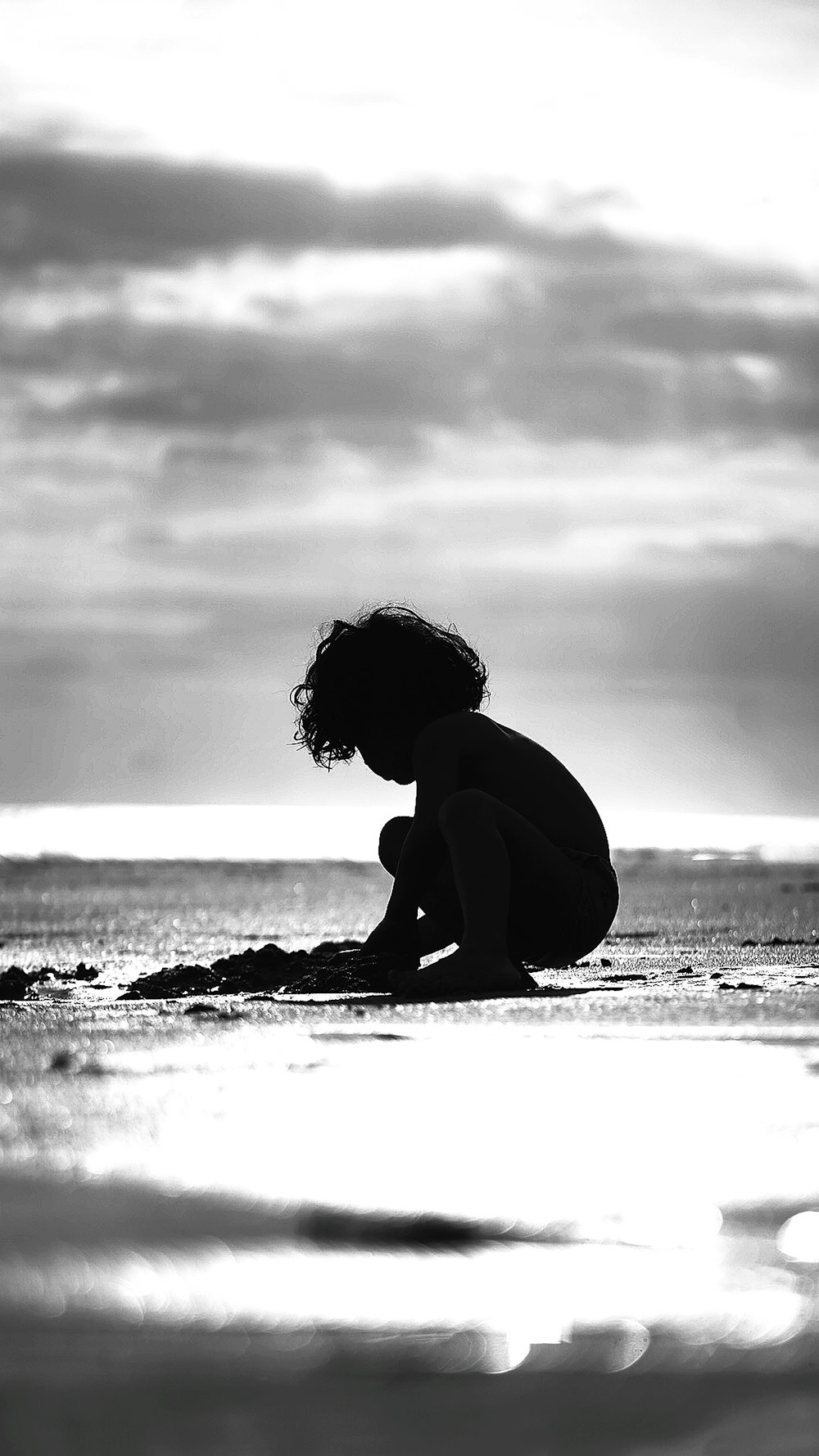 grayscale photo of woman sitting on beach