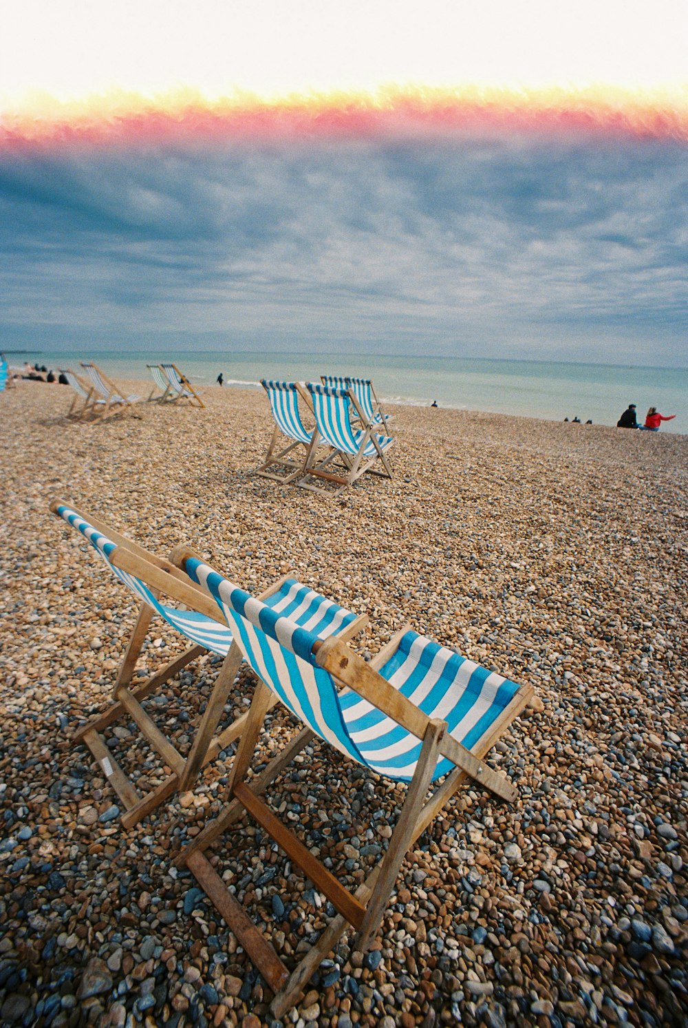 white and blue beach chairs on brown sand during daytime