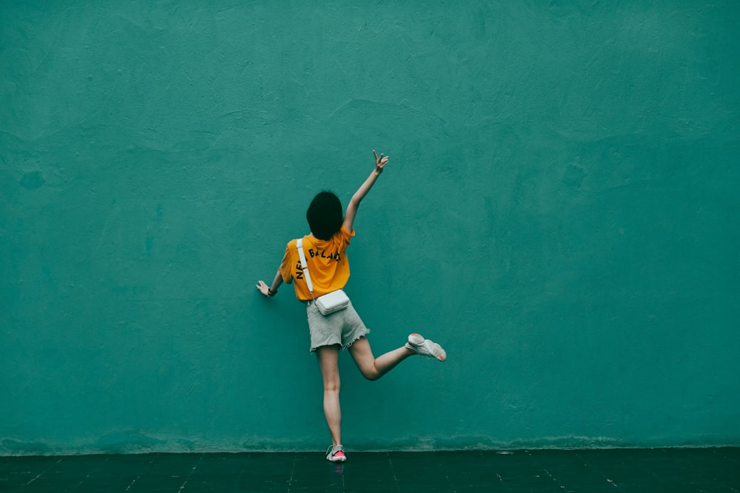 boy in yellow t-shirt and white shorts running on green concrete floor