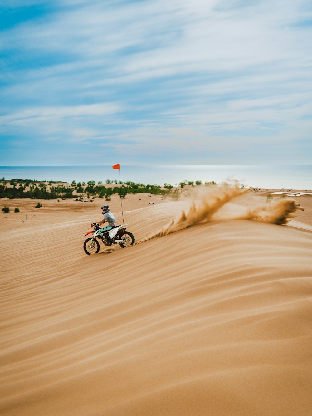 昼間、茶色の砂浜でバイクに乗る男