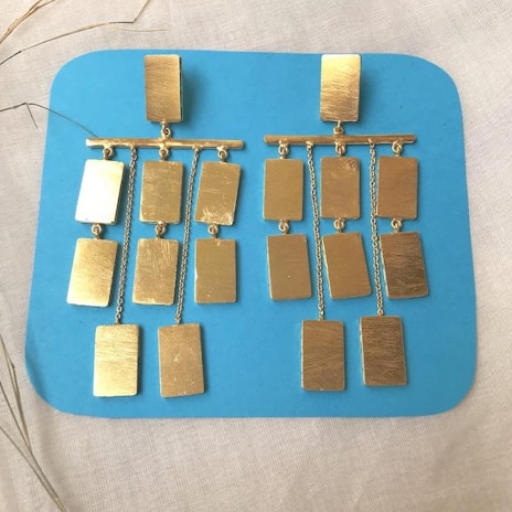 Modern geometric earrings in mixed metals displayed on a crisp white linen cloth