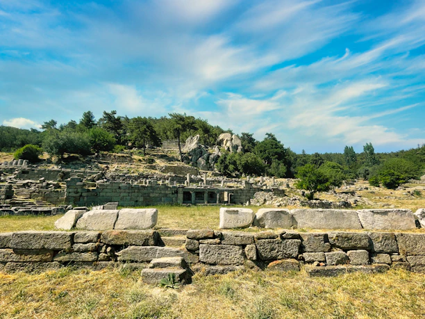 Ancient stone ruins surrounded by lush green hills under a bright sky.