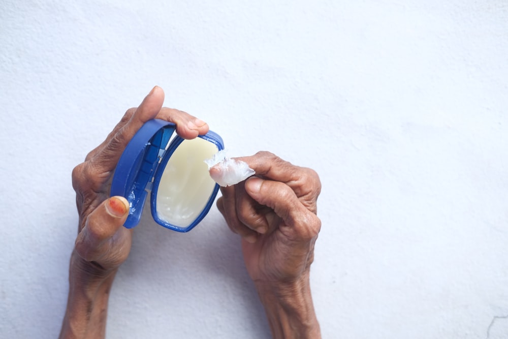 person holding blue and white plastic container