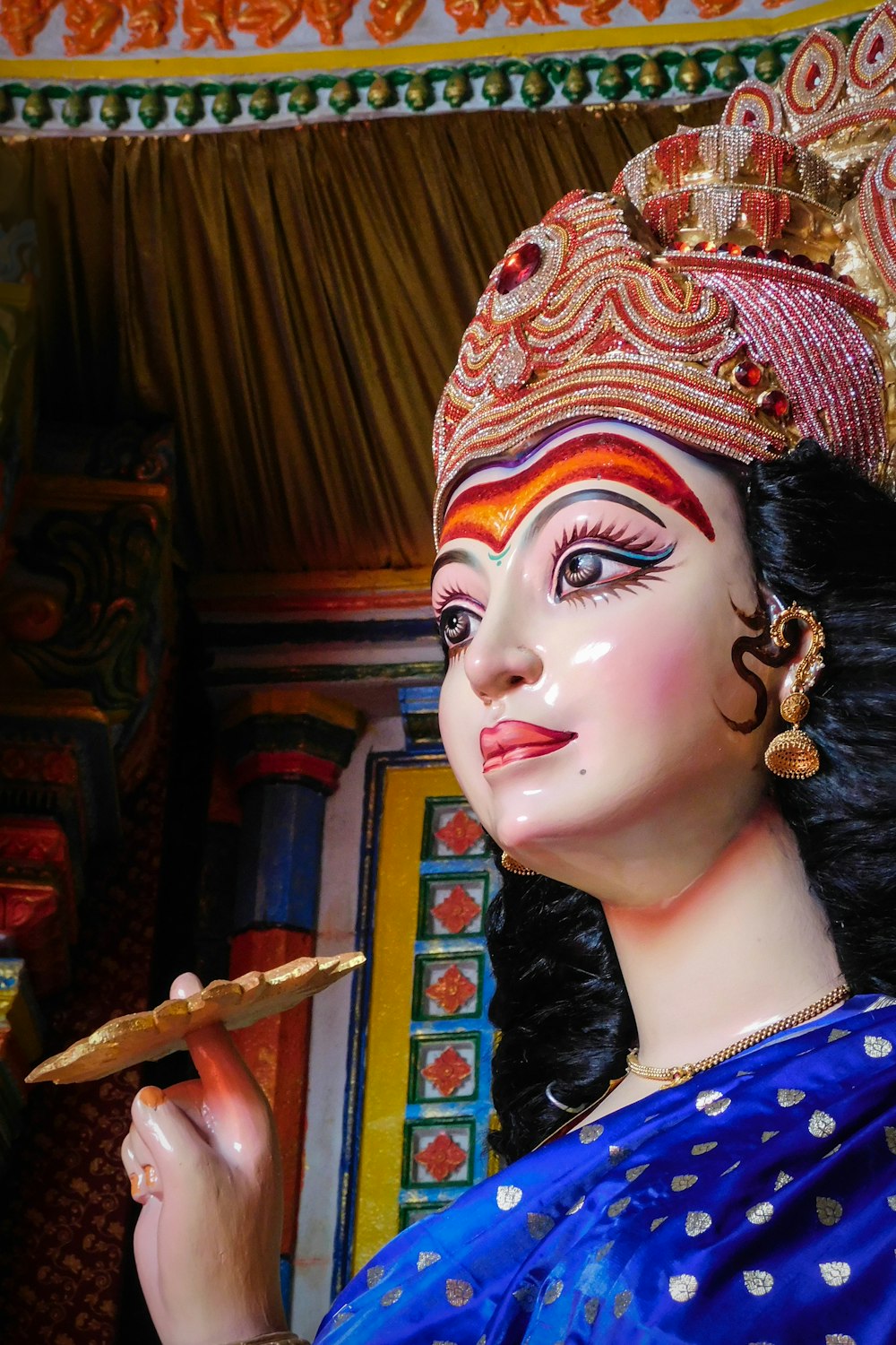 woman in blue and white shirt wearing red and gold headdress